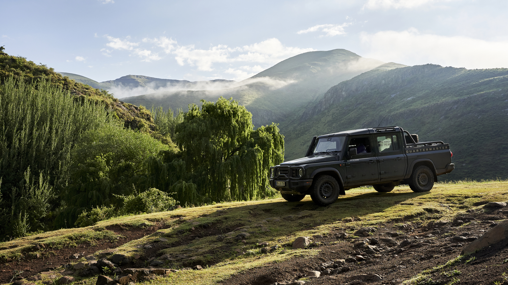 INEOS Grenadier Quartermaster parked on a grassy hilltop with mist rolling through the Lesotho mountains in the background.