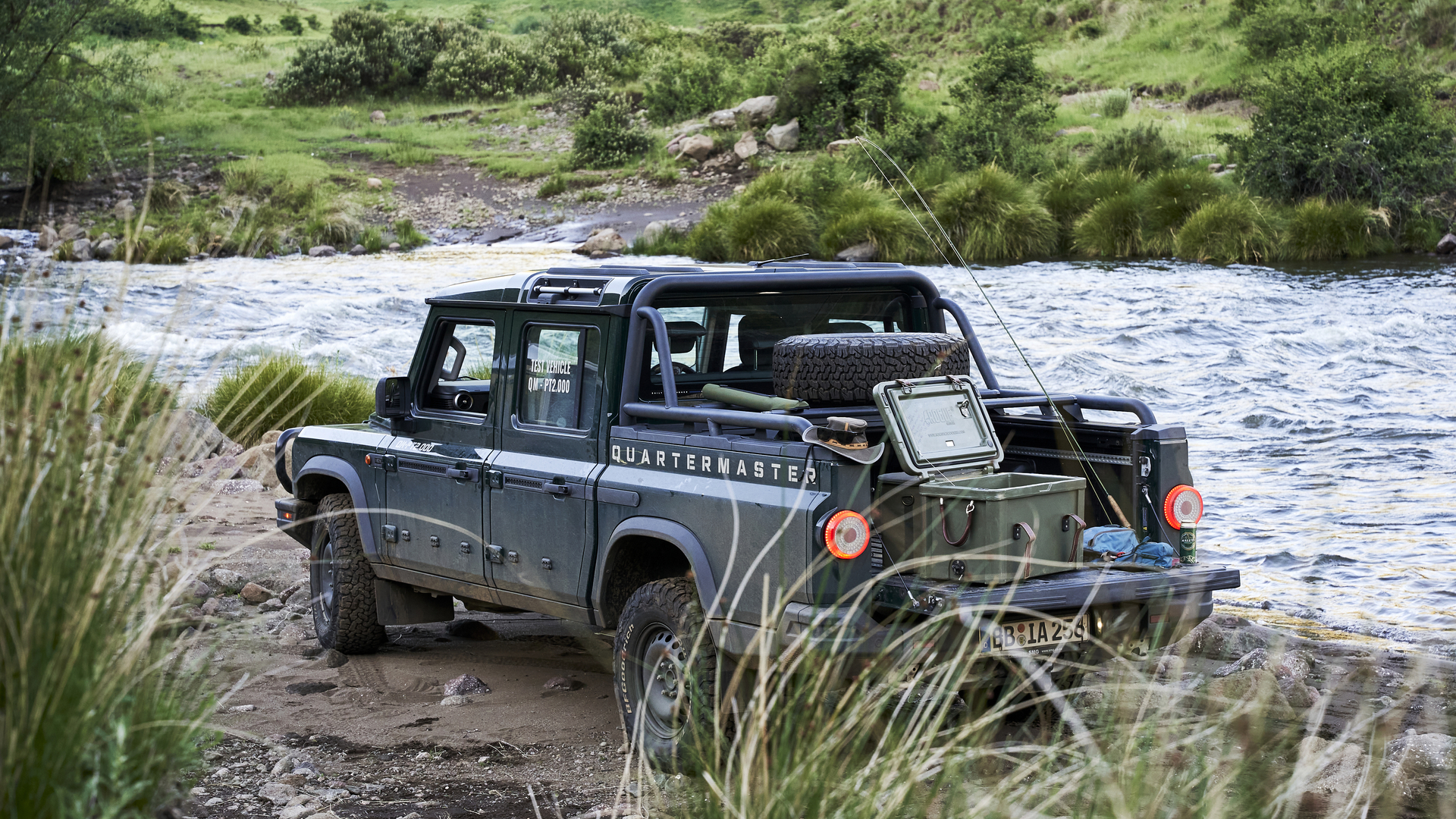 INEOS Grenadier Quartermaster at the river’s edge, loaded with gear, ready for fishing in a remote Lesotho landscape.